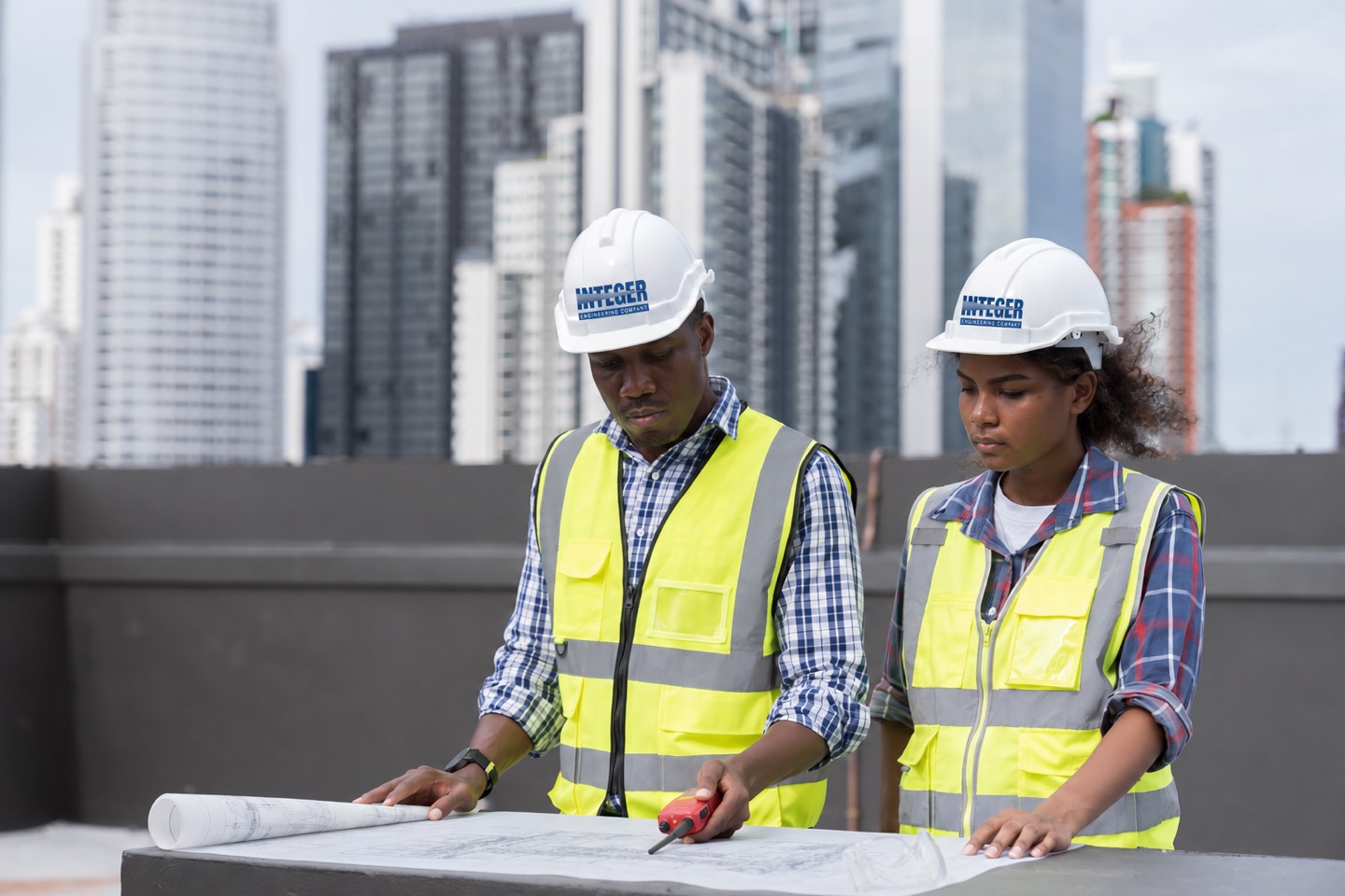 Two engineers in hard hats reviewing drawings on site